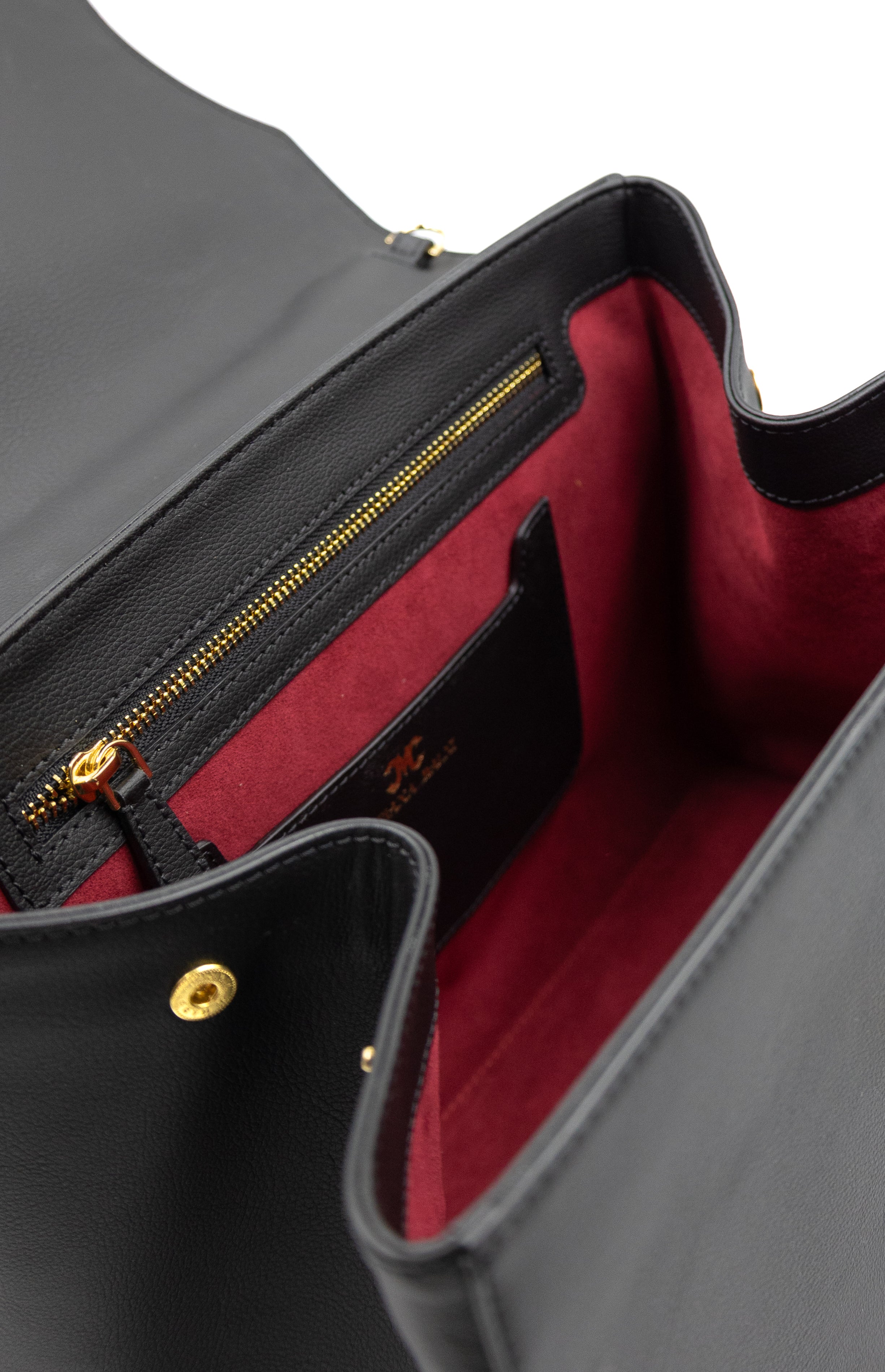 Inside view of a Mariana Malni Paget handbag showing the deep burgundy Alcantara microfibre lining sourced via Nona Source (LVMH Paris), gold zipper hardware, and embossed MM monogram.